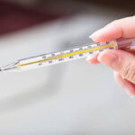 Close-up hand holding on thermometer for checking patient.